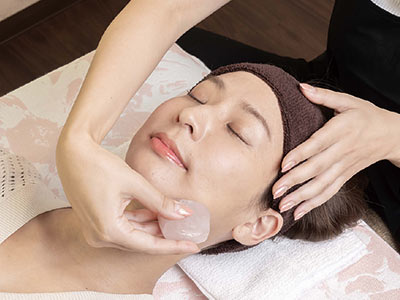 【小顔サロン Riry okinawa】施術風景　ローズクォーツカッサでマッサージ